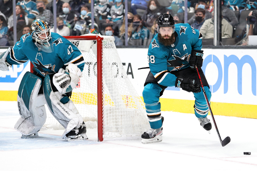 Brent Burns (88) looks while controlling the puck. James Reimer looks on from the Sharks Net.