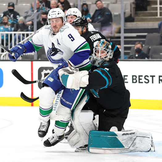 J.T. Miller (9) collides with Sharks goalie James Reimer (47)