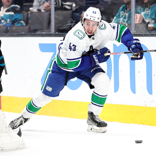 Quinn Hughes chases the puck behind the net.