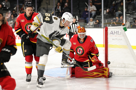 Brendan Brisson (24) tries to tip a puck past Heat goalie Adam Werner (35) as Connor Zary (47) defends