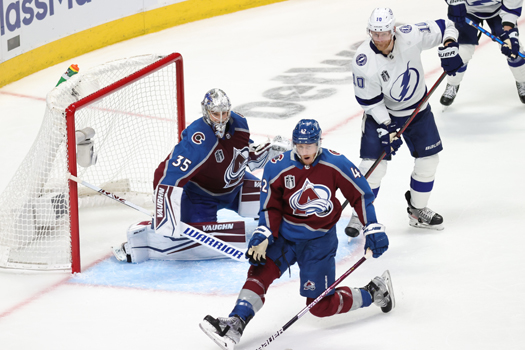 Josh Manson (42) tries to block a shot in front of Avalanche goalie Darcy Kuemper