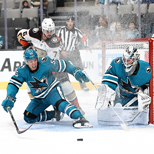 Derrick Pouliot (55) looks to clear the rebound away from Josh Mahura (76) and Sharks' goalie James Reimer