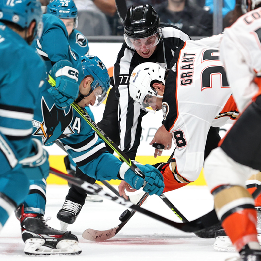 Linesman Caleb Apperson drops the puck on a faceoff between Nick Bonino (13) and Derek Grant (38)