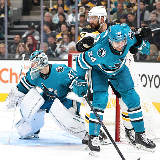 Nick Foligno (center) cross-checks Sharks defenseman Jaycon Megna (24) as he tries to get position in front of the net