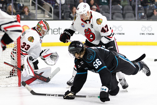 Icehogs goalie Drew Commesso (33) stops a backhanded shot attempt by Ethan Cardwell (56) as defenseman Josh Healey (47) provides support