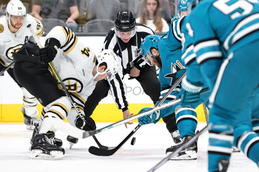 Linesman Caleb Apperson drops the puck on a faceoff between Jake DeBrusk (left) and Luke Kunin (right)