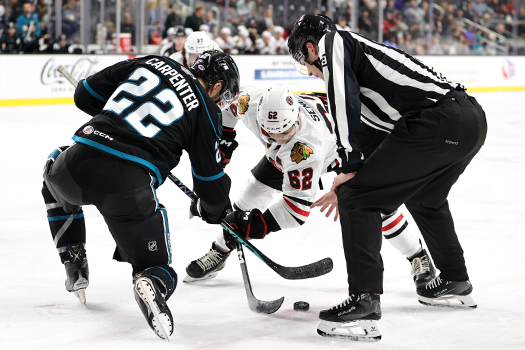 Linesman Joseph Mahon drops the puck on a faceoff between Ryan Carpenter (22) and Brett Seney (62)