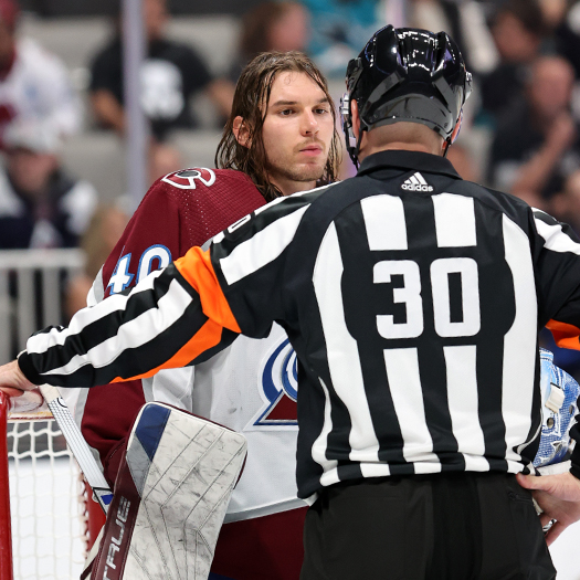 Referee Kendrick Nicholson talks to Avalanch goalie Alexander Georgiev after he loses his mask for the second time during play
