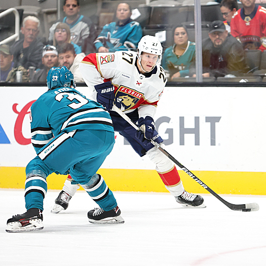 Eetu Luostarinen (27) attempts to move the puck around Sharks defenseman Calen Addison (33)