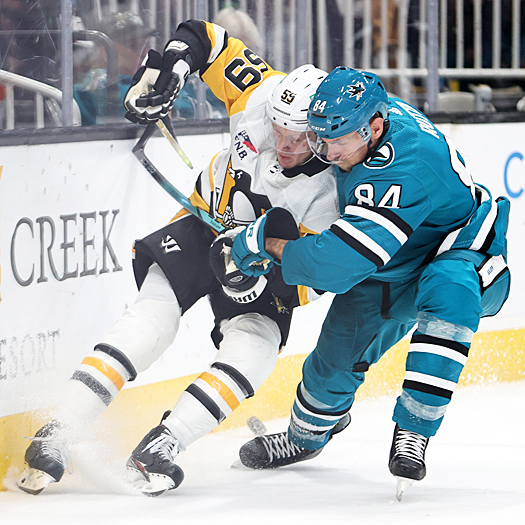 Jake Guentzel (59) and Jan Rutta (84) battle for puck possession behind the net