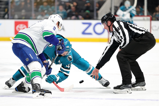 Linesman Caleb Apperson drops the puck on a face-off between Elias Petersson (40) and Mikael Granlund (64)