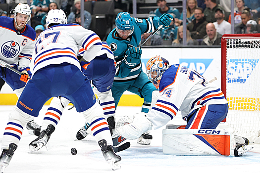 Oilers goalie Stuart Skinner reaches to cover a rebound in front of Sharks forward Ryan Carpenter (22) as Brett Kulak (27 ) defends