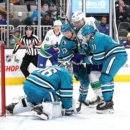 Sharks goalie Kaapo Kahkonen covers the puck as Sharks Calen Addison (33) and Luke Kunin (11) contain Ilya Mikheyev (65)