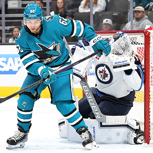 Jets goalie Laurent Brossoit gets his glove on a shot as Kevin Labanc (62) attempts to provide a screen