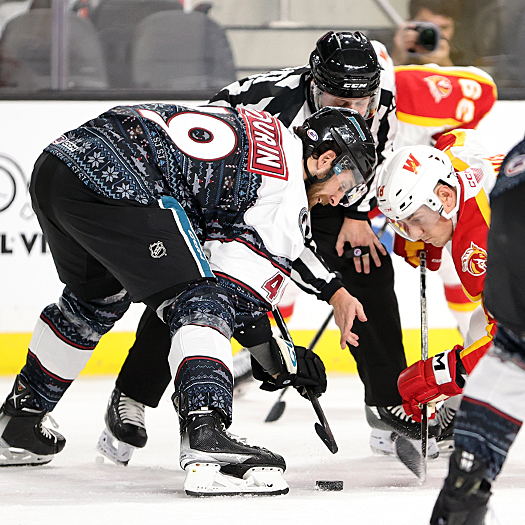 Linesman Jake Rennert drops the puck on a face-off between Scott Sabourin (49) and Ben Jones (right)