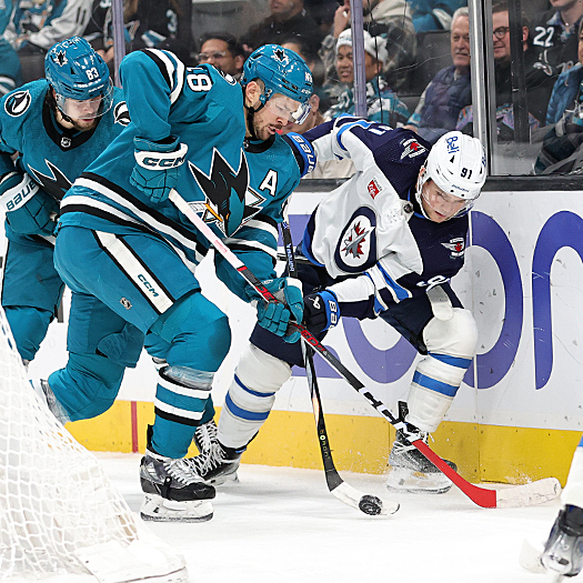Tomas Hertl (48) and Cole Perfetti (91) fight for the puck behind the net