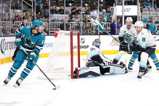 Kraken goalie Joey Daccord slides to cover the open net as Mike Hoffman (68) looks to pass as defenseman Jordan Dumoulin (8) looks to provide defensive support