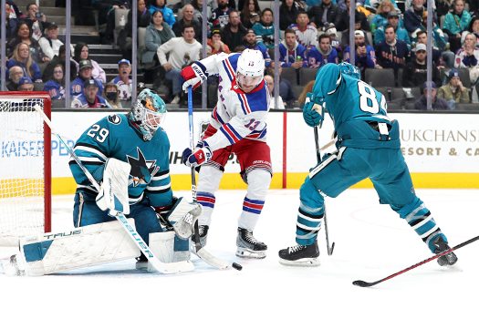 Rangers forward Alexis Lafreniere (left) attempts to control a rebound in front of goalie Mackenzie Blackwood as defenseman Jan Rutta (84) provides support