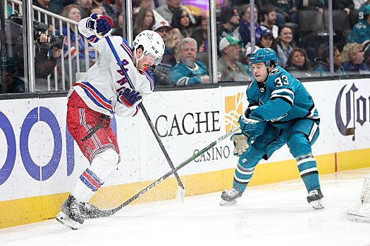 Rangers forward Alexis Lafreniere (left) attempts to control the puck as Sharks defenseman Calen Addison (33) moves in to apply pressure