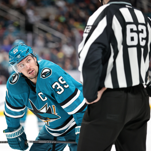 Sharks captain Logan Couture looks up at linesman Mitch Hunt prior to a face-off