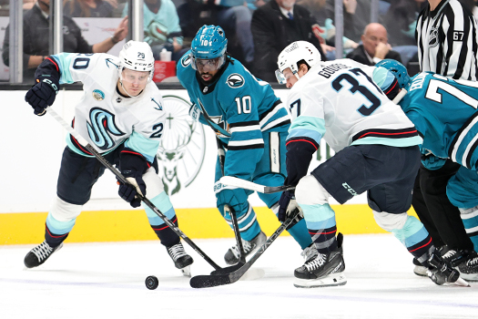 Sharks forward Anthony Duclair attempts to maneuver between Kraken players Eeli Tolvane (20) and Yanni Gourde (37)