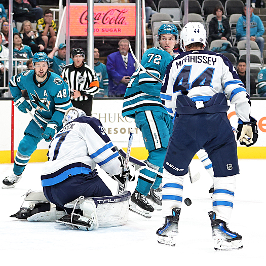 Sharks forward William Eklund (72) jumps to attempt to screen goalie Connor Hellebuyck as Josh Morrissey (44) looks for the rebound