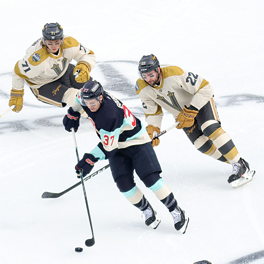 Yanni Gourde (37) skates the puck up ice in front of Golden Knights Michael Amadio (22) and William Karlsson (71)