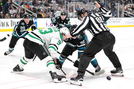 Linesman Tyson Baker attempts to avoid the puck on a face-off between Wyatt Johnston (53) and William Eklund (72)