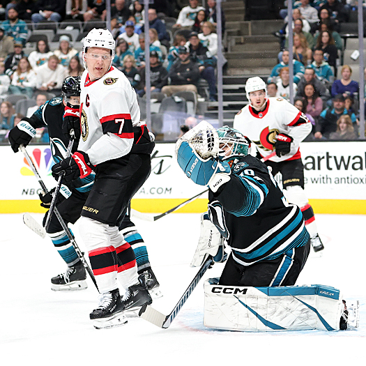 Senators captain Brady Tkachuk (7) looks back as Sharks goalie Magnus Chrona makes a glove save