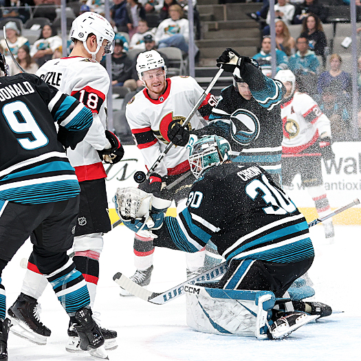 Sharks goalie Magnus Chrona reaches for the puck as Tim Stutzle (18) looks for a rebound